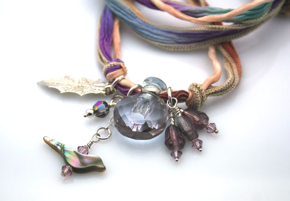 close-up photo of the light purple mini-perfume bottle, and the silver and antique beads
