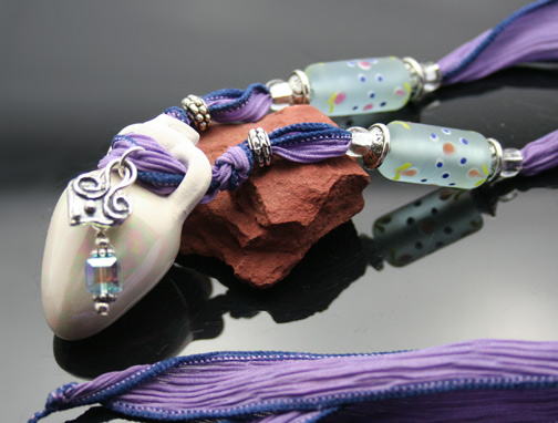 beautiful aromatherapy necklace with purple silk ribbon, charms and glass beads