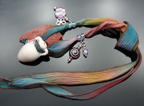 aromatherapy vessel necklace on a rainbow silk ribbon