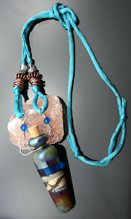a beautiful aroma pendant on a silk cord with silver, copper, and glass beads