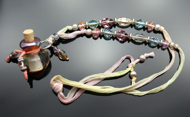 A beautiful blush-colored glass aromatherapy bottle necklace on pink watercolor silk cord with fantasic glass beads