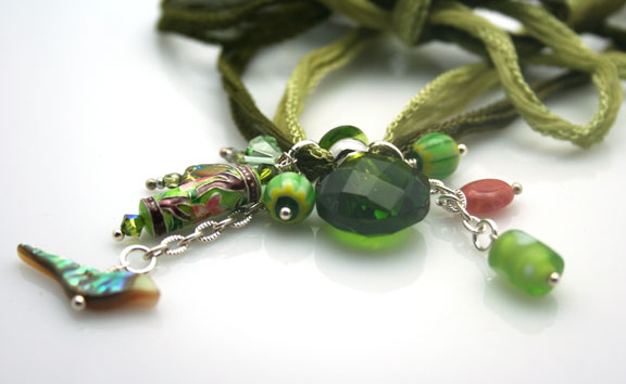 close-up photo of the mini faceted perfume bottle and artistically selected beads on hand-dyed green silk ribbons